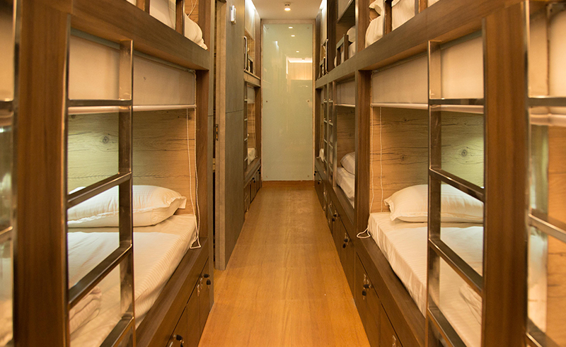 Corridor of wood-panelled bunk pods with reading lights